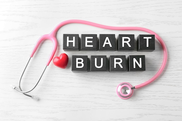 나무 배경에 큐브와 청진기로 만든 텍스트 HEART BURN