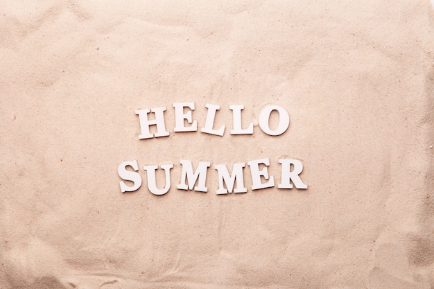 Testo hello summer da lettere bianche sulla sabbia. concetto di ora legale.