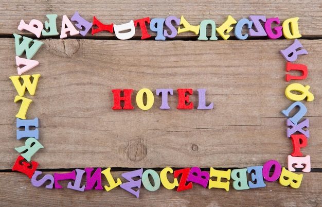 Text HOTEL of colored wooden letters on a wooden background