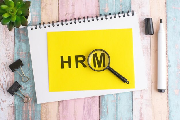 text HRM under a magnifying glass on a yellow background top view the text is written in black marker