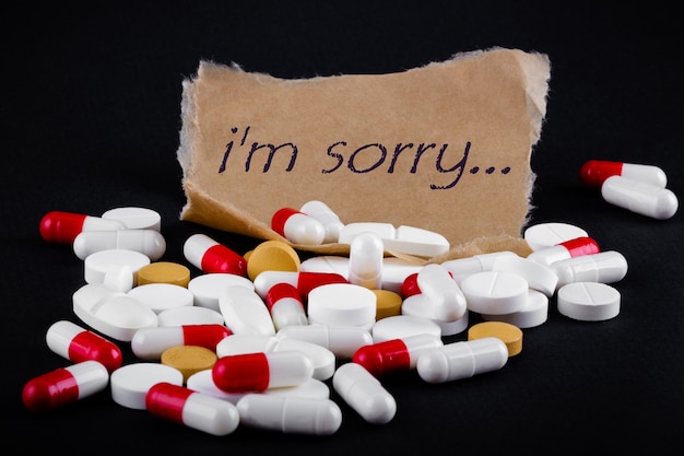 Фото Текст извините на листе бумаги рядом с кучей таблеток тетрадь смерти концепция самоубийства