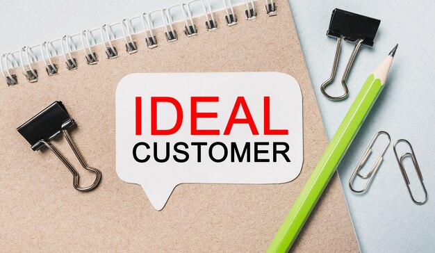 Text IDEAL CUSTOMER on a white sticker with office stationery