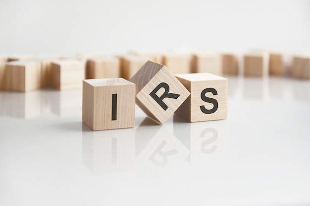 Text IRS on wooden blocks with letters on a white background reflection of the caption on the mirrored surface of the table