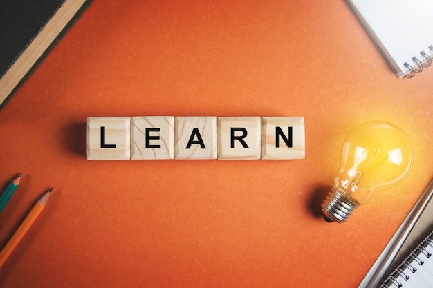 Text LEARN on wooden block cube with light bulb