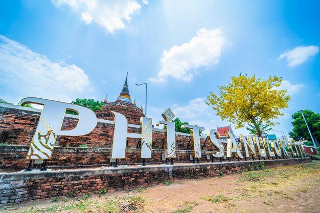 Photo text letter light phitsanulok city and golden cassia fistula flowers at park in phra chedi luang in temple wat ratchaburana is a major tourist attraction in phitsanulok thailanddaytime blue sky