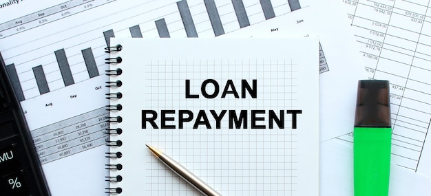 Text LOAN REPAYMENT on the page of a notepad on financial charts