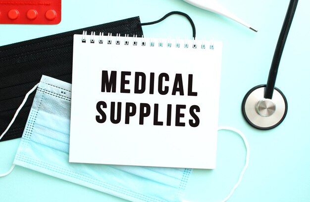 The text medical supplies is written in a notebook that lies on a blue background