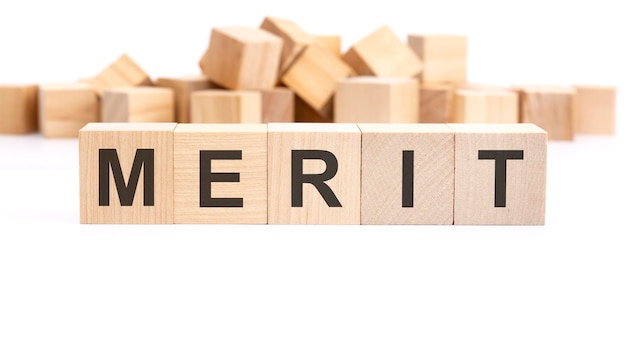 Text MERIT made of wooden cubes and different words on white background