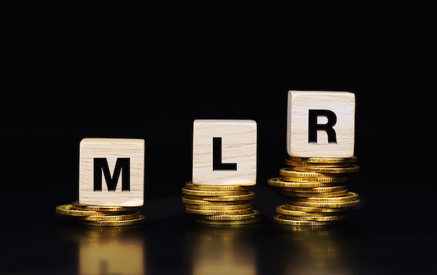 Text MLR (Minimum Loan Rate) on wooden blocks on stack of gold coins, Business concept. interest rat