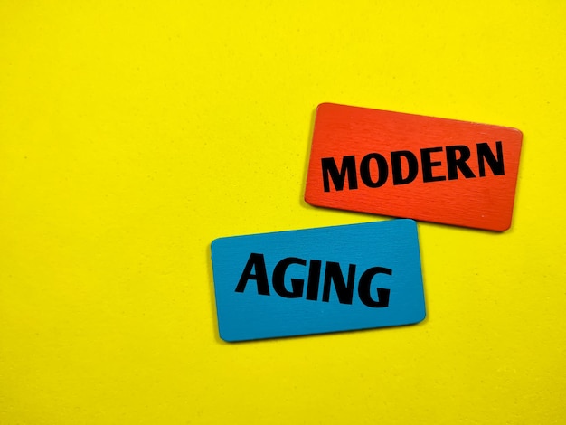 텍스트 MODERN AGING은 노란색 배경의 색상이 지정된 나무 판자에 쓰는 최신 사진 개념입니다.