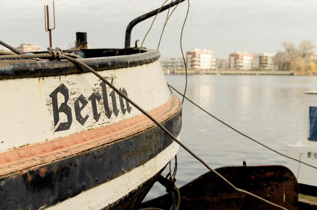 Text on moored boat on river against sky