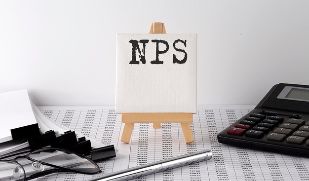 Text NPS on easel with office tools and paper.Top view. Business concept