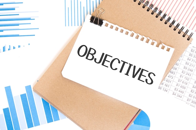 Photo text objectives on white paper sheet and brown paper notepad on the table with diagram. business concept