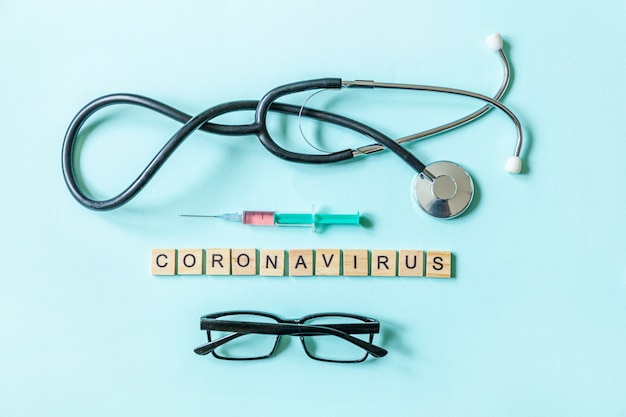 Text phrase Coronavirus syringe eyeglasses and stethoscope on blue pastel wall. Novel coronavirus 2019-nCoV MERS-Cov covid-19 middle East respiratory syndrome coronavirus virus vaccine concept.