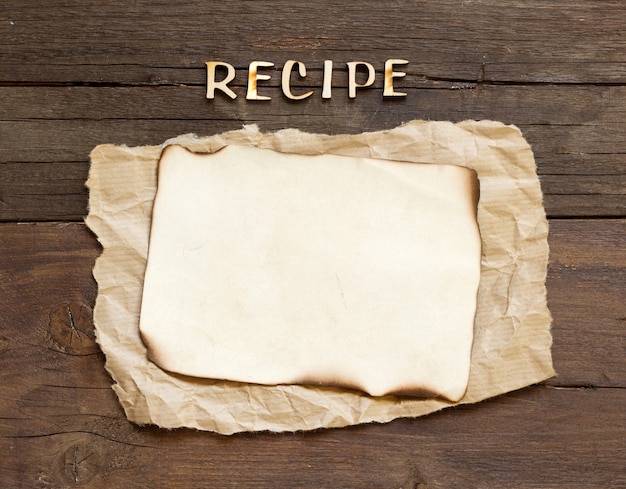 Text RECIPE made of wooden letters and paper on a wooden background top view