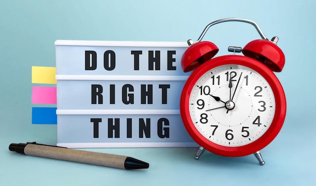 Text Do the right thing written on the lightbox with alarm clock and colorfull stickers on blue background