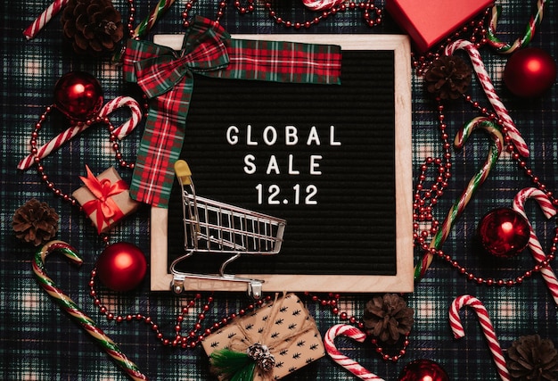 The text of the sale 12.12 on the Christmas decor letter board with a credit card and a mini grocery cart. Design to promote the winter sale at the end of the year. Top view.