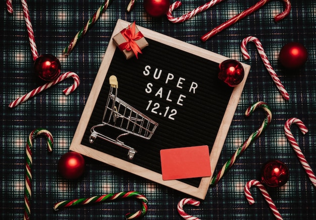 The text of the sale 1212 on the Christmas decor letter board with a credit card and a mini grocery cart Design to promote the winter sale at the end of the year Top view