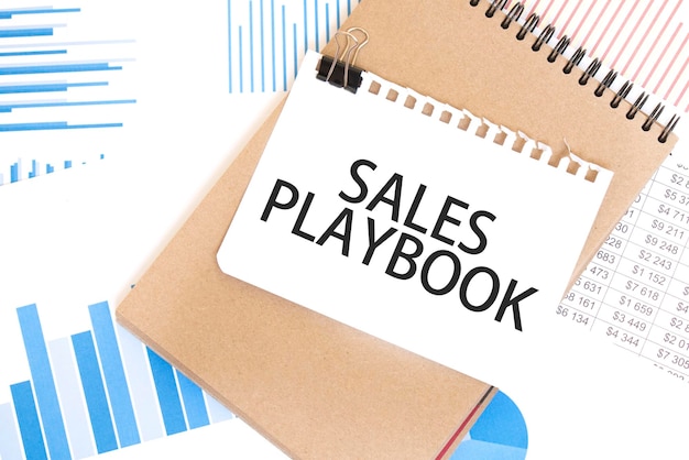 Photo text sales playbook on white paper sheet and brown paper notepad on the table with diagram business concept