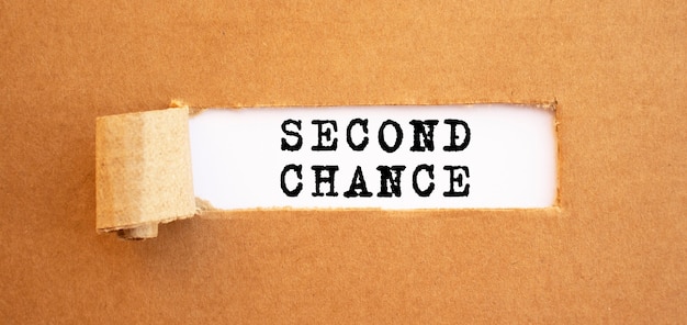 Text SECOND CHANCE appearing behind torn brown paper. For your design, concept.