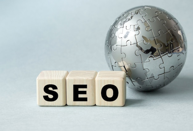 Text SEO . Globe and wooden cubes on a gray table. The concept of global search engine optimization