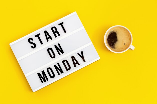 Text "start on monday" on lightbox and cup of coffee. concept of new beginnings. Start of working week.