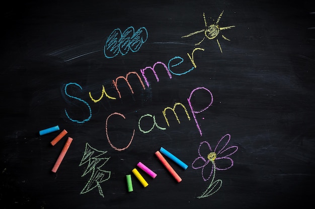 Photo text summer camp written on black chalkboard with chalk sticks of different colors