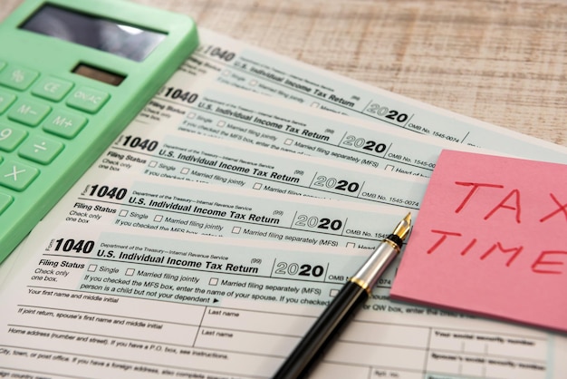 Text tax time on sticker with calculator on 1040 tax form 2020 2021