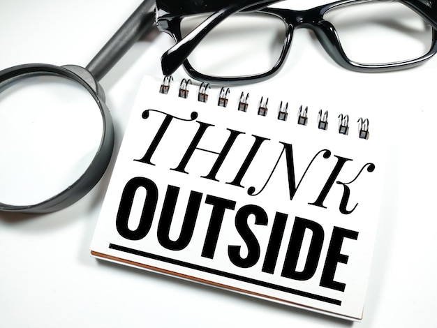 Text THINK OUTSIDE with magnifying glass and glasses on white backgroundBusiness concept