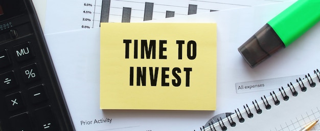 オフィスの机の財務チャートにあるメモ帳のページに「投資する時間」とテキストを入力します。電卓の近く。