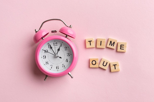 The text Time out and a pink alarm clock on pink background Business concept photo