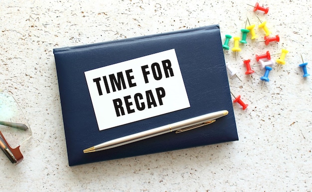 眼鏡の横にある青いノートに横たわっている名刺の「TIME FOR RECAP」というテキスト