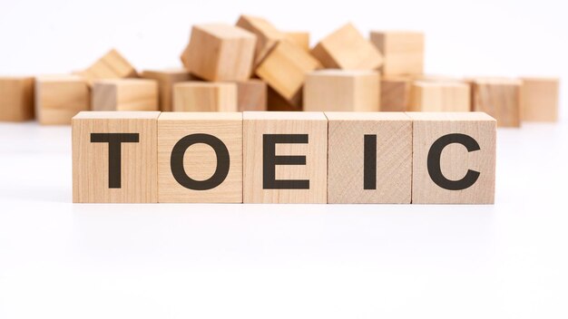 Text TOEIC made of wooden cubes and different words on white background concept of studying English