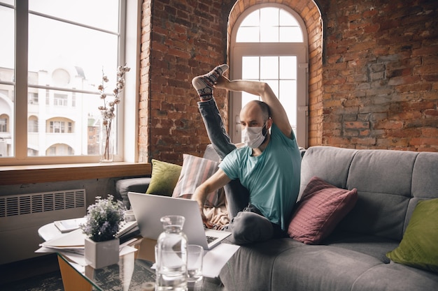 Text typing Young man doing yoga at home while being quarantine and freelance online working