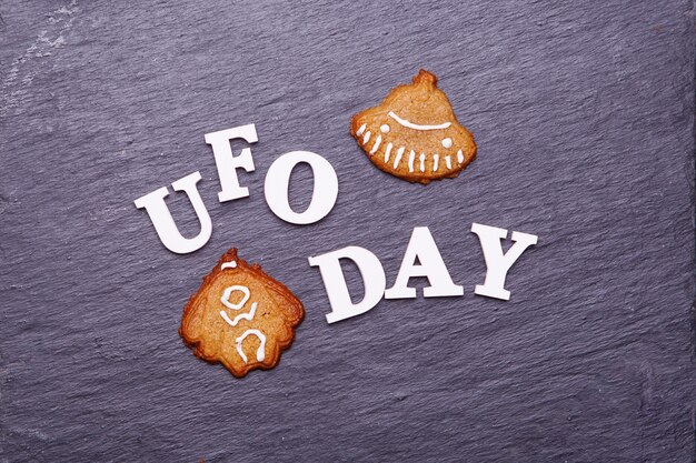 空飛ぶ円盤とエイリアンの形でUFOの日とクッキーをテキストで送信します。 UFOの日の概念