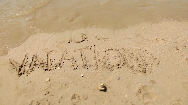 Текст отпуск, написанный на песке морского пляжа крупным планом