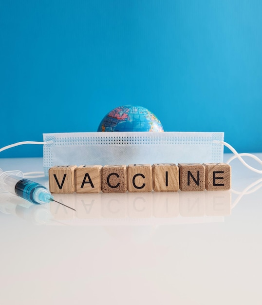 Text vaccine medical mask syringe and globe on background