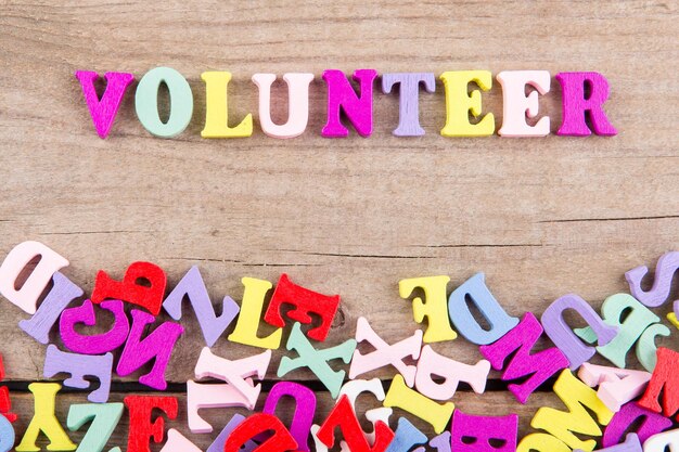 Text Volunteer of colored wooden letters on a wooden background