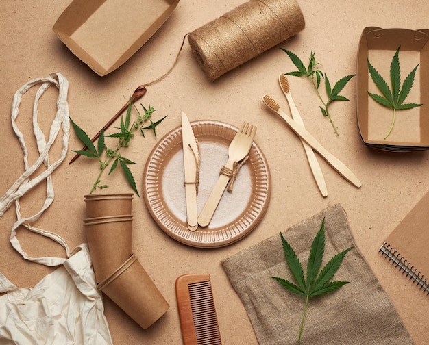 Foto sacchetto tessile e stoviglie usa e getta in carta marrone, foglie di canapa verde su un baio di legno