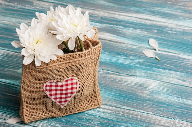 Photo textile heart and bouquet of flowers in rough burlap bag