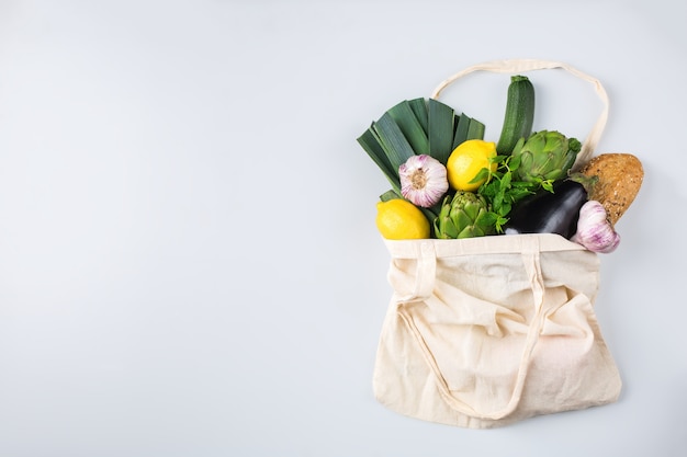 Textile mesh bag with produce, fruits and vegetables. Zero waste, eco-friendly, plastic free recycled, reusable concept. Copy space, flat lay bleached coral background