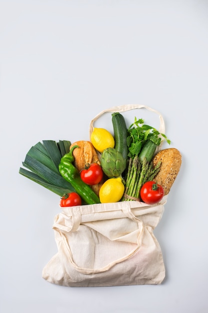 農産物、果物、野菜が入ったテキスタイルメッシュバッグ。ゼロウェイスト、環境にやさしい、プラスチックフリーのリサイクル、再利用可能なコンセプト。コピースペース、白化したサンゴの背景を平らに置く