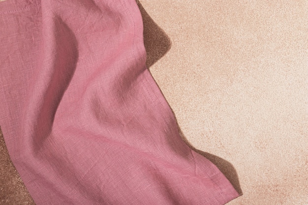 Textile pink serving napkin on beige plastered background