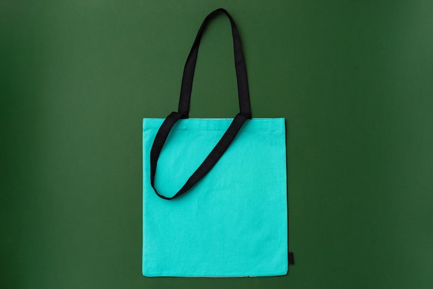 Textile shopping bag on green background flat lay