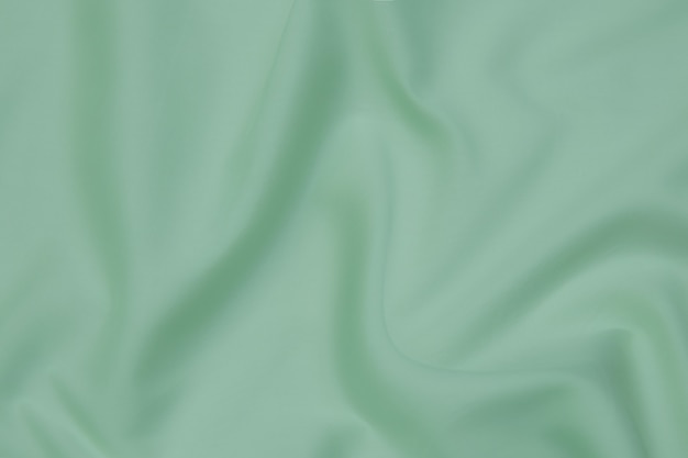 Текстура, фон, узор. Текстура зеленой шелковой ткани. Красивая изумрудно-зеленая мягкая шелковая ткань.