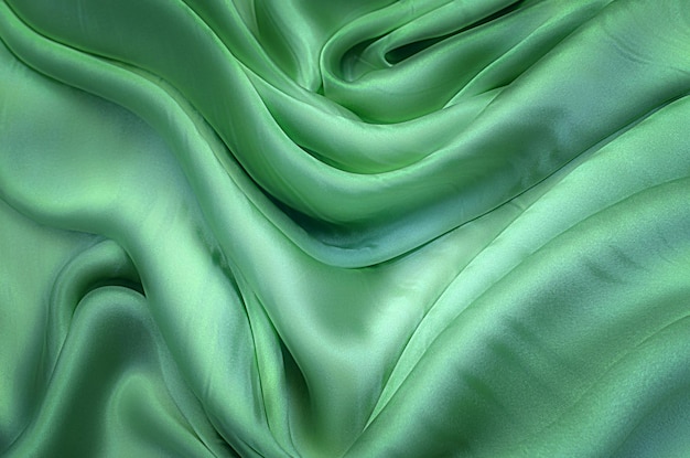 Texture, background, pattern. Texture of green silk fabric. Beautiful emerald green soft silk fabric.