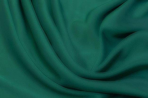 Texture, background, pattern. Texture of green silk fabric. Beautiful emerald green soft silk fabric.