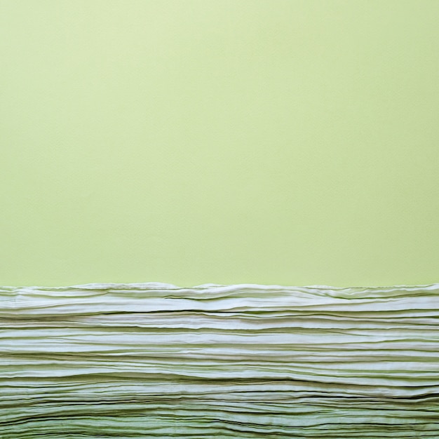 Текстура фонового рисунка зеленой гофрированной ткани с параллельными или диагональными складками на фактурной бумаге