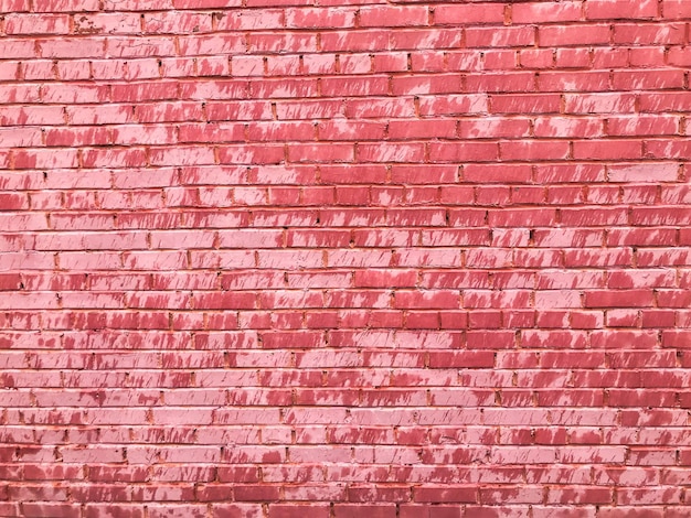 Texture of a beautiful unique unusual pink tender old cracked brick wall of rectangular bricks with seams painted with pink old shabby paint The background