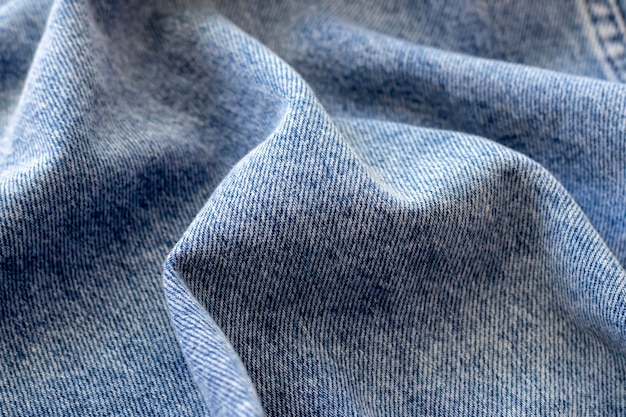 The texture of blue denim folded in waves in closeup